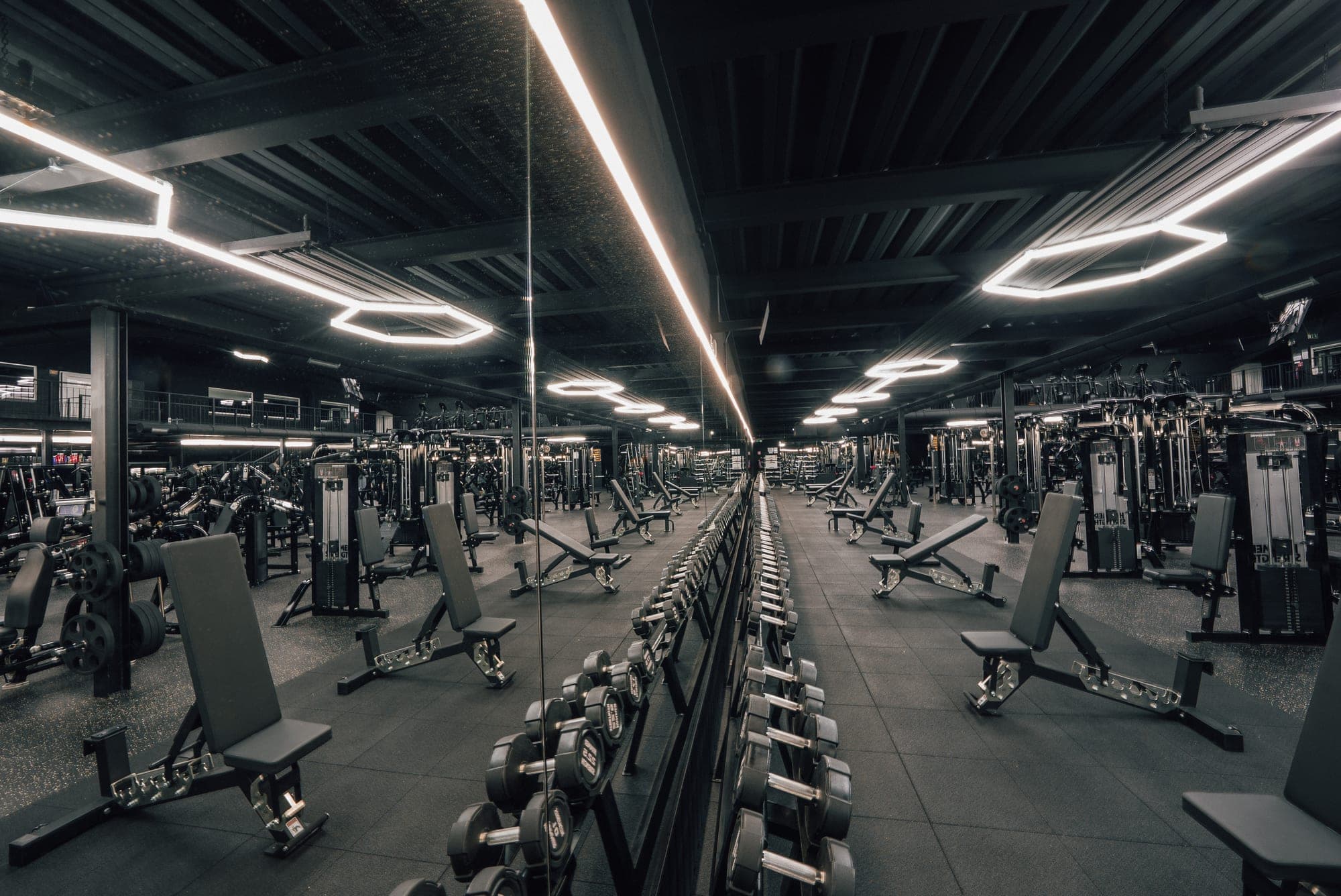 Letecký pohľad na tréningovú arénu Gladiator Gym — stroje a voľné váhy v čierno-zlatej hale